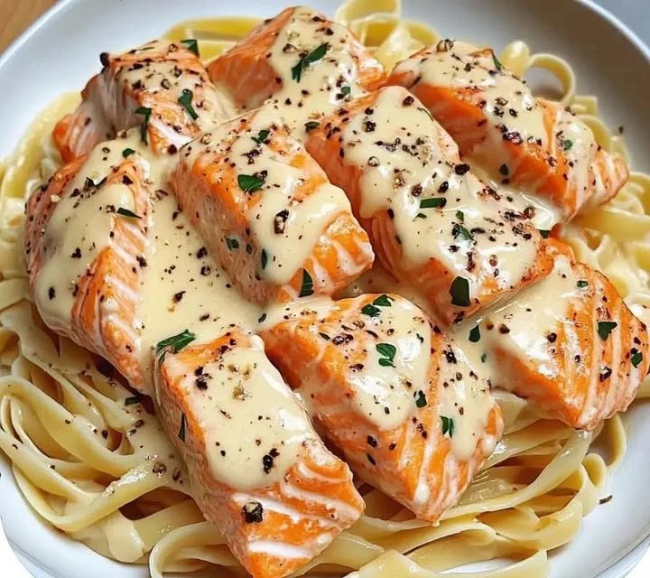 Creamy garlic salmon pasta dish garnished with fresh herbs.